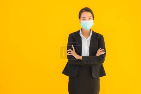 Foto de Retrato hermosa joven negocio asiático mujer usar máscara para proteger covid19 coronavirus en amarillo aislado fondo - Imagen libre de derechos