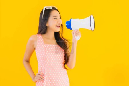 Photo for Portrait beautiful young asian woman speak loud with megaphone on yellow isolated background - Royalty Free Image