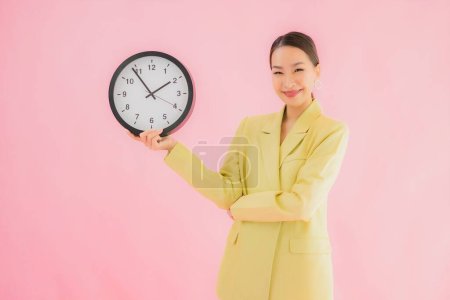 Téléchargez les photos : Portrait belle jeune femme d'affaires asiatique montrer horloge ou alarme sur fond isolé couleur - en image libre de droit
