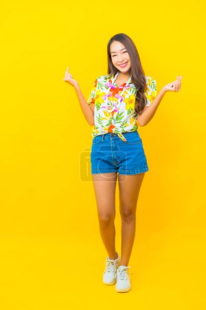 Téléchargez les photos : Portrait belle jeune femme asiatique porter chemise colorée sur fond jaune pour le festival sonkran en Thaïlande - en image libre de droit