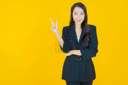 Photo for Portrait beautiful young asian woman with call center customer care service center on yellow color background - Royalty Free Image
