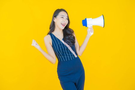 Téléchargez les photos : Portrait belle jeune femme asiatique sourire avec mégaphone sur fond de couleur - en image libre de droit