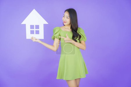 Foto de Retrato hermosa joven mujer asiática con casa o casa cartel de papel sobre fondo de color - Imagen libre de derechos