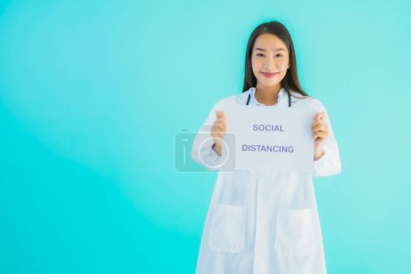 Photo for Portrait beautiful young asian doctor woman with sign paper with social distancing word for protect from covid19 or coronavirus - Royalty Free Image