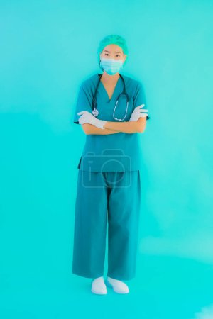 Foto de Retrato hermosa joven asiática médico mujer con máscara y gafas para proteger de covid19 o coronavirus sobre fondo aislado azul - Imagen libre de derechos