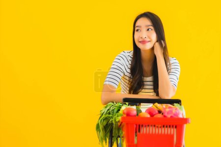 Téléchargez les photos : Portrait belle jeune asiatique femme shopping épicerie de supermarché et chariot sur fond jaune isolé - en image libre de droit