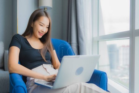 Photo for Portrait beautiful young asian woman use laptop on sofa in living room area - Royalty Free Image