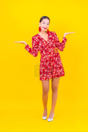 Portrait beautiful young asian woman smile in action in chinese new year concept on color background