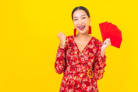 Téléchargez les photos : Portrait belle jeune femme asiatique avec des enveloppes rouges sur fond jaune - en image libre de droit