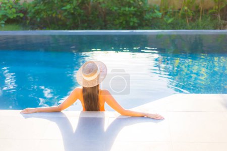 Téléchargez les photos : Portrait belle jeune femme asiatique profiter de se détendre autour de la piscine pour des vacances de loisirs - en image libre de droit