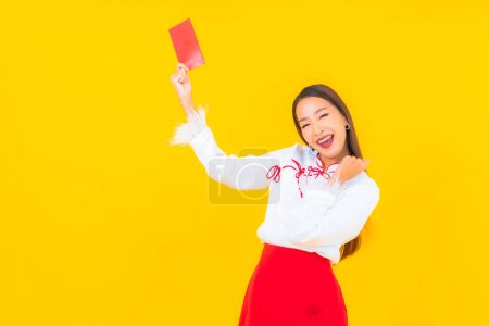 Foto de Retrato hermosa joven mujer asiática con sobres rojos carta en chino año nuevo sobre fondo amarillo - Imagen libre de derechos