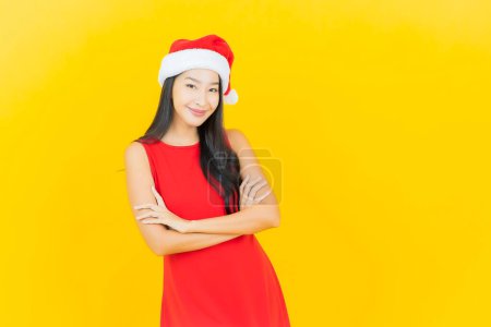 Téléchargez les photos : Portrait belle jeune femme asiatique porter santa chapeau ou bandeau sur fond de couleur jaune - en image libre de droit