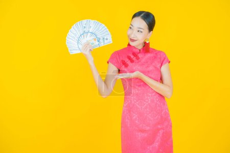 Téléchargez les photos : Portrait belle jeune femme asiatique sourire avec beaucoup d'argent et d'argent sur fond de couleur - en image libre de droit