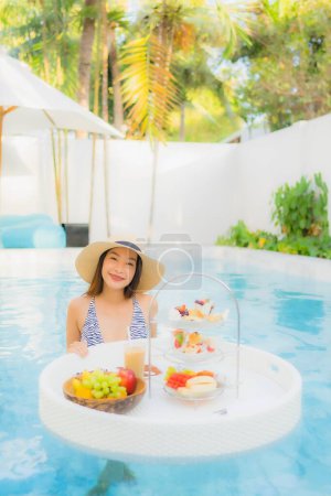 Photo for Portrait beautiful young asian woman enjoy with afternoon tea or breakfast floating on swimming pool in hotel resort - Royalty Free Image