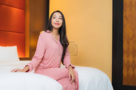 Téléchargez les photos : Portrait belle jeune asiatique femme relax sourire heureux sur lit dans chambre intérieur - en image libre de droit