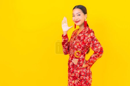 Portrait beautiful young asian woman smile in action in chinese new year concept on color background