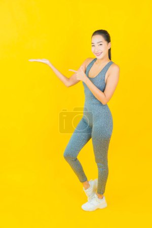 Téléchargez les photos : Portrait belle jeune femme asiatique avec des vêtements de sport prêt pour l'exercice sur fond jaune - en image libre de droit