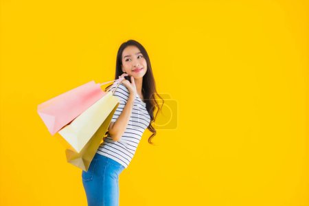 Foto de Retrato hermosa joven mujer asiática con colorido bolso de compras sobre fondo aislado amarillo - Imagen libre de derechos