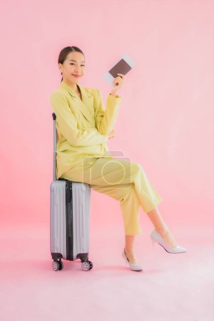 Téléchargez les photos : Portrait belle jeune femme d'affaires asiatique avec sac à bagages et passeport sur fond de couleur - en image libre de droit