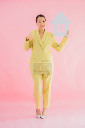Foto de Retrato hermosa joven asiática mujer de negocios mostrar casa o casa signo en color aislado fondo - Imagen libre de derechos