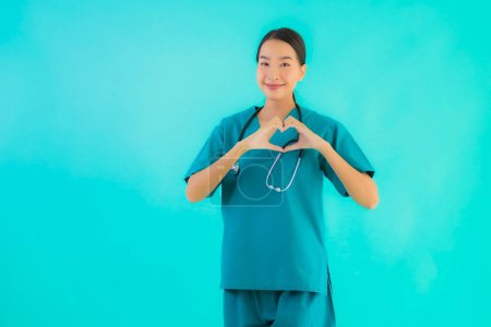 Foto de Retrato hermosa joven asiático médico mujer feliz sonrisa mostrar corazón forma para trabajo en hospital y clínica en azul aislado fondo - Imagen libre de derechos