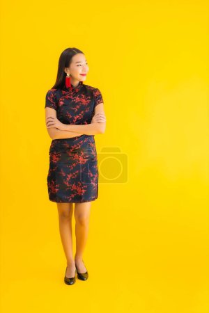 Porträt schöne junge asiatische Frau tragen chinesisches Kleid mit Aktion für chinesisches Neujahrskonzept auf gelbem Hintergrund