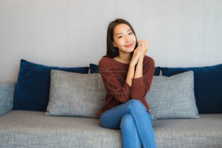 Photo for Portrait beautiful young asian woman relax smile on sofa in living room interior - Royalty Free Image