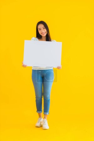 Photo for Portrait beautiful young asian woman show empty white billboard sign on yellow isolated background - Royalty Free Image