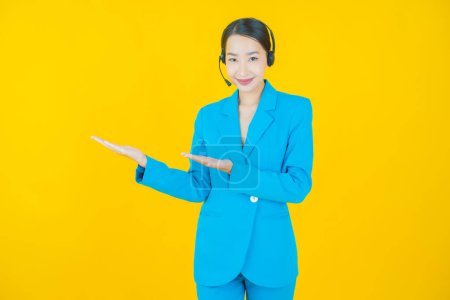 Porträt schöne junge asiatische Frau mit Call Center Kundenbetreuungszentrum auf gelbem Hintergrund