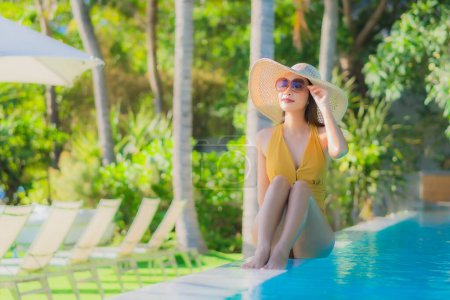 Téléchargez les photos : Portrait belle jeune femme asiatique sourire heureux se détendre autour de la piscine extérieure dans la station hôtelière pour les vacances de loisirs Voyage - en image libre de droit