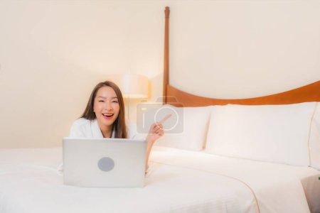 Photo for Portrait beautiful young asian woman use laptop on bed in bedroom interior - Royalty Free Image