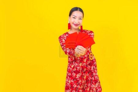 Porträt schöne junge asiatische Frau mit roten Umschlägen auf gelbem Hintergrund