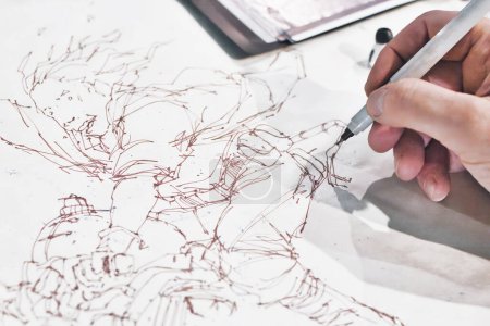 Foto de Primer plano de la mano de un artista de cómic pintando un personaje de dibujos animados manga en línea de tinta dibujo - Imagen libre de derechos