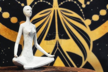 Una estatua de madera blanca de una mujer sentada con las piernas cruzadas sobre un fondo kármico y cósmico del espacio - concepto de cuerpo y mente misticismo llano astral