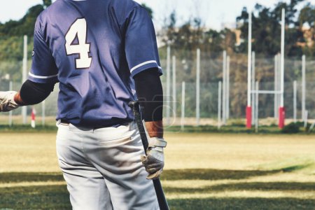 Photo for Rear view of a baseball player holding a bat wearing a team uniform on a sports field pitch - Royalty Free Image