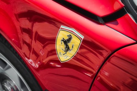 Foto de Vista lateral de un coche deportivo de lujo de la marca Ferrari rojo con el logotipo del caballo negro pegatina en el cuerpo, sin personas - Imagen libre de derechos