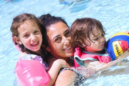 Photo for A closeup shot of a cheerful white Caucasian family in the swimming pool - mother, son and daughter enjoying summer - Royalty Free Image