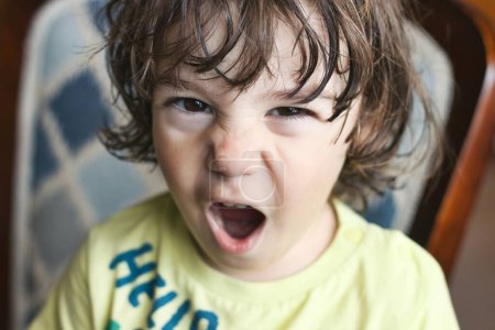 Photo for Closeup headshot portrait of a young white Caucasian boy throwing a temper tantrum, looking directly at the camera with an angry expression on his face - Royalty Free Image
