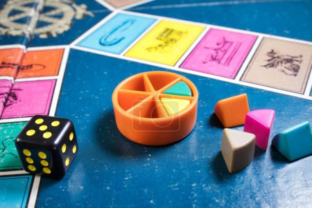 Photo for London, UK - 07 April 2019: A board games tournament - Close-up of classic board game Trivial Pursuit with black die and colored plastic pieces of different colors - Royalty Free Image