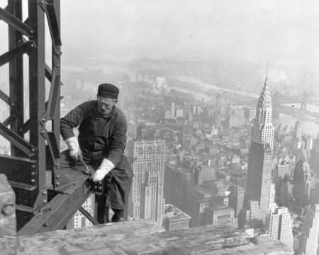 Téléchargez les photos : New York, États-Unis - 1930 : Un Blanc célibataire d'âge moyen de race blanche travaillant seul sur une poutre en acier dans un immeuble de grande hauteur à New York avec l'Empire State building visible en arrière-plan - Photo de Lewis Hine - en image libre de droit