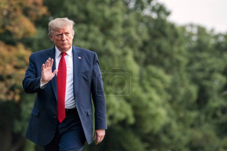 Foto de Washington DC, Estados Unidos - 21 de agosto de 2019: un presidente de aspecto serio, Donald Trump, camina por el césped de la Casa Blanca, agitando su mano en gesto de saludo - Imagen libre de derechos