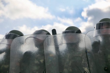 Riot police forming a line carrying perspex shields and wearing helmets