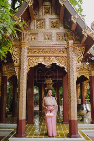 Mujer en traje tailandés de pie dentro de un famoso templo budista antiguo hito en Chiang Mai