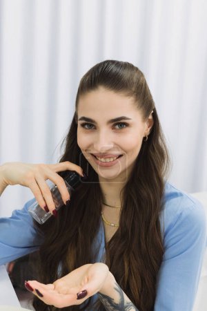 Téléchargez les photos : Cosmetic dermatologist is shown applying a skin treatment product from a bottle onto her hands with a smile, ready to provide the best care for her patients. - en image libre de droit