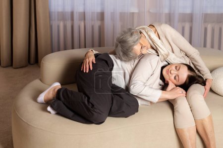 Una abuela o anciana y una nieta o niña están teniendo una conversación dulce y amistosa mientras están sentadas en un sofá. Familia fuerte, amorosa y feliz.