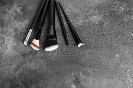 Set of makeup brushes, cosmetics, makeup tools on a dark gray spotted background. flat lay, top view. Poster 652916764