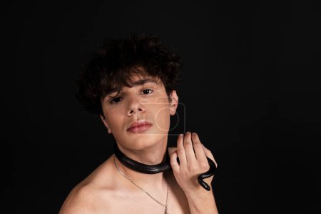 Foto de Joven hombre guapo con el torso desnudo, con una serpiente negra arrastrándose alrededor de su cuello. Aislado sobre fondo negro. - Imagen libre de derechos