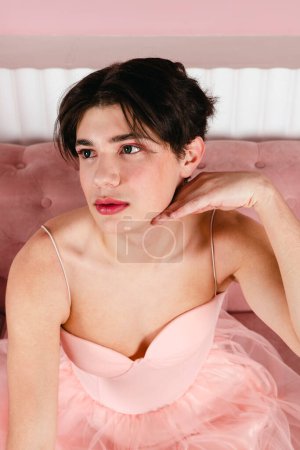 Foto de Primer plano Retrato de un gay tierno con un vestido rosa. Joven homosexual glamour con maquillaje posando en un traje femenino. disparo en la cabeza. - Imagen libre de derechos