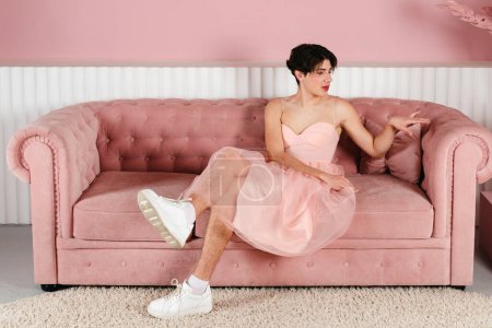 Foto de Retrato de un gay tierno con un vestido rosa. Glamour homosexual joven chico con maquillaje posando en un traje femenino. - Imagen libre de derechos