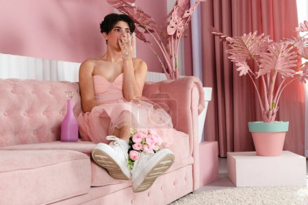 Foto de Retrato de un gay tierno vestido de rosa, bebiendo alcohol. Glamour homosexual joven chico con maquillaje posando en un traje femenino. - Imagen libre de derechos